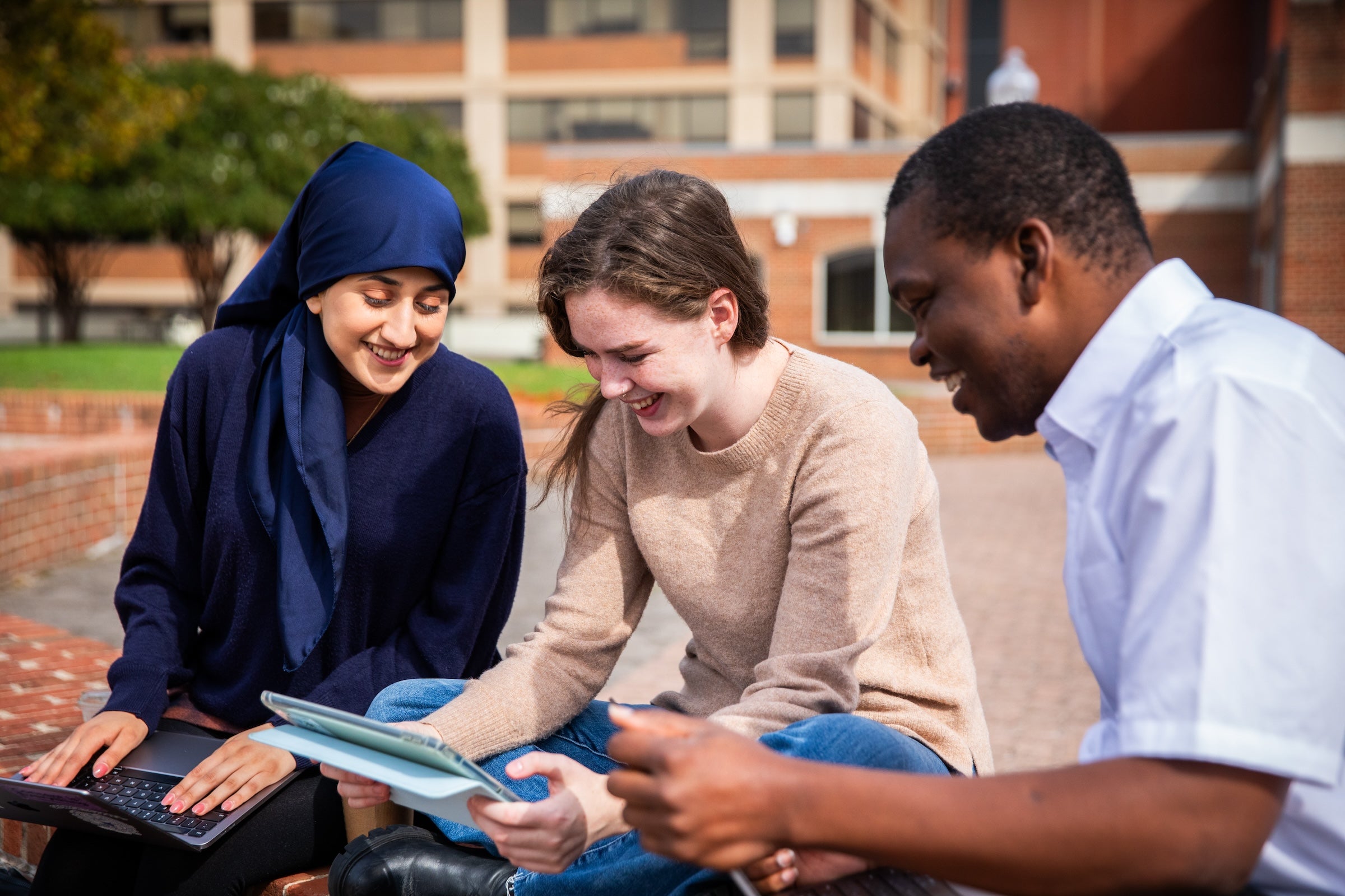 Three Georgetown Conflict Resolution students looking at a notebook smiling
