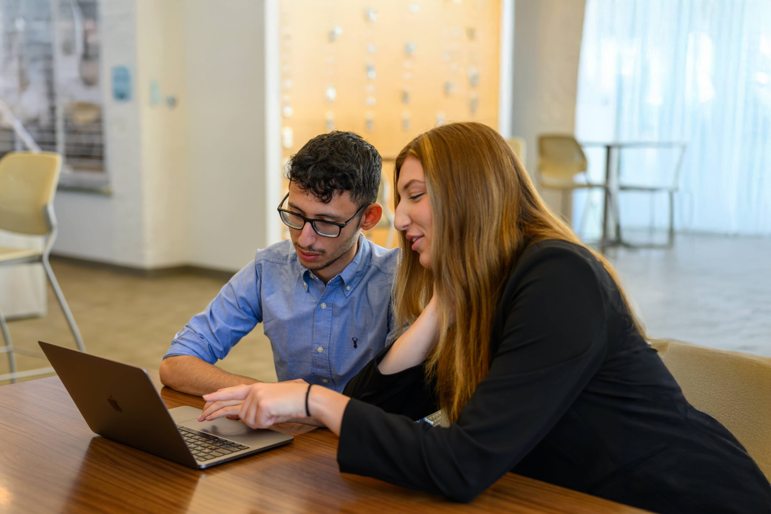 Two government students looking at a laptop together.
