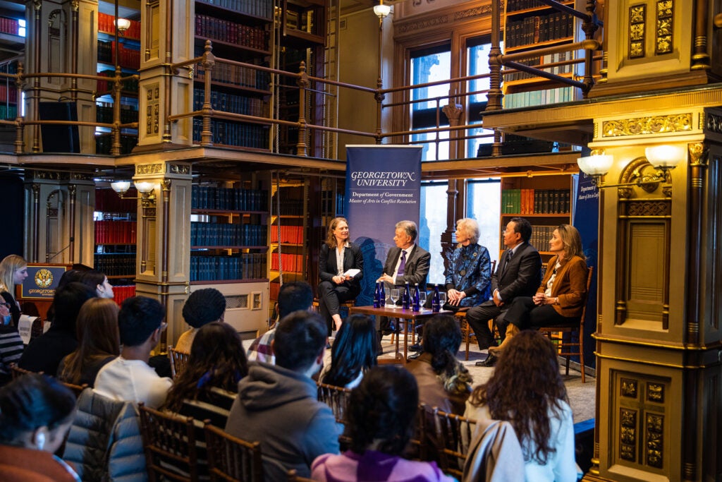 Photo from 2023 Doomsday Clock Town Hall hosted on January 24, 2023 in Riggs Library with Professor Katy Collin and panelists Mary Robinson, Elbegdorj Tsakhia, Juan Manuel Santos, and Rachel Bronson. The panelists sit facing an audience. 
