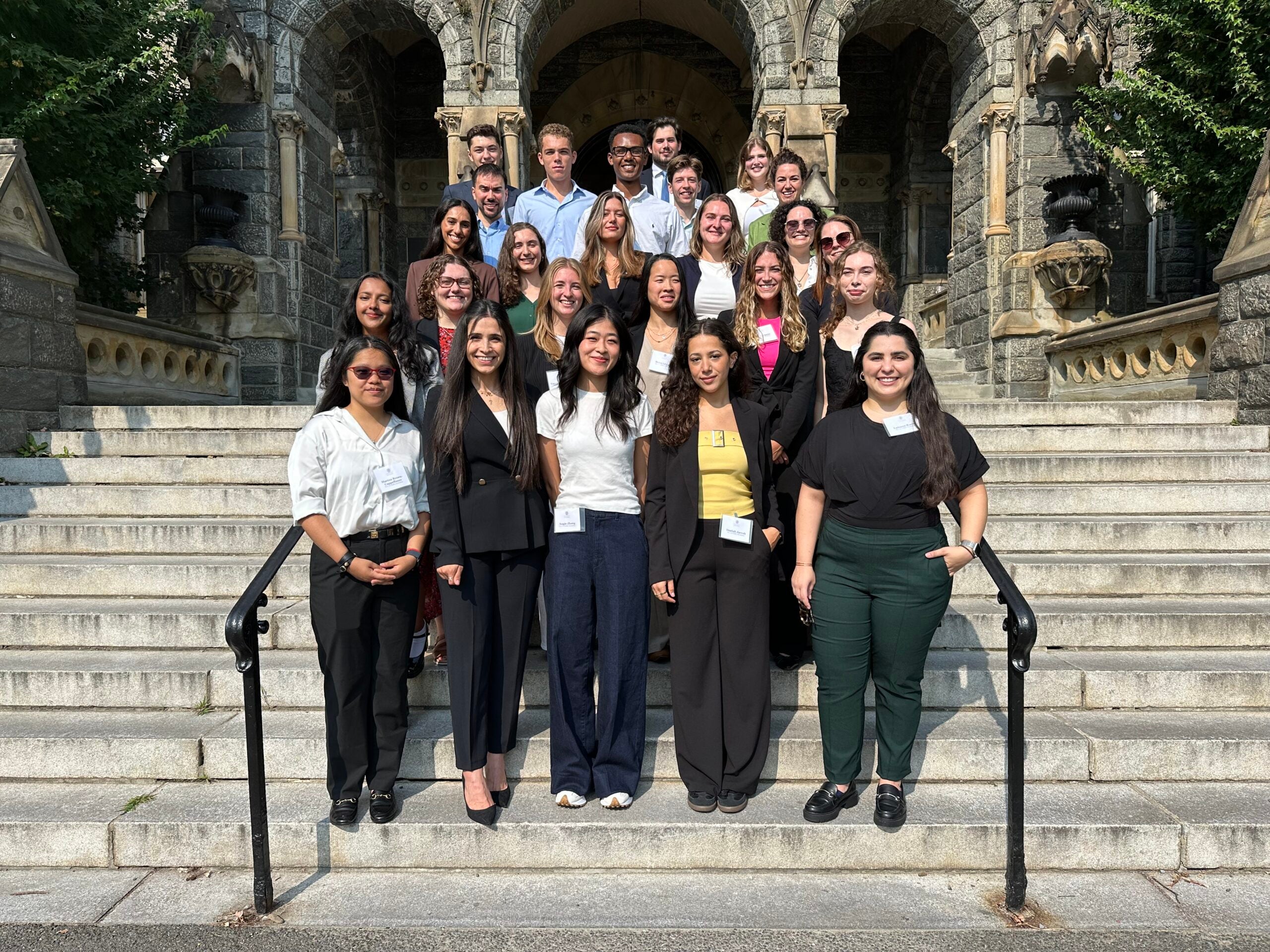 MA in Conflict Resolution Class of 2025. Twenty-four master's students standing on the steps of Healy Hall.