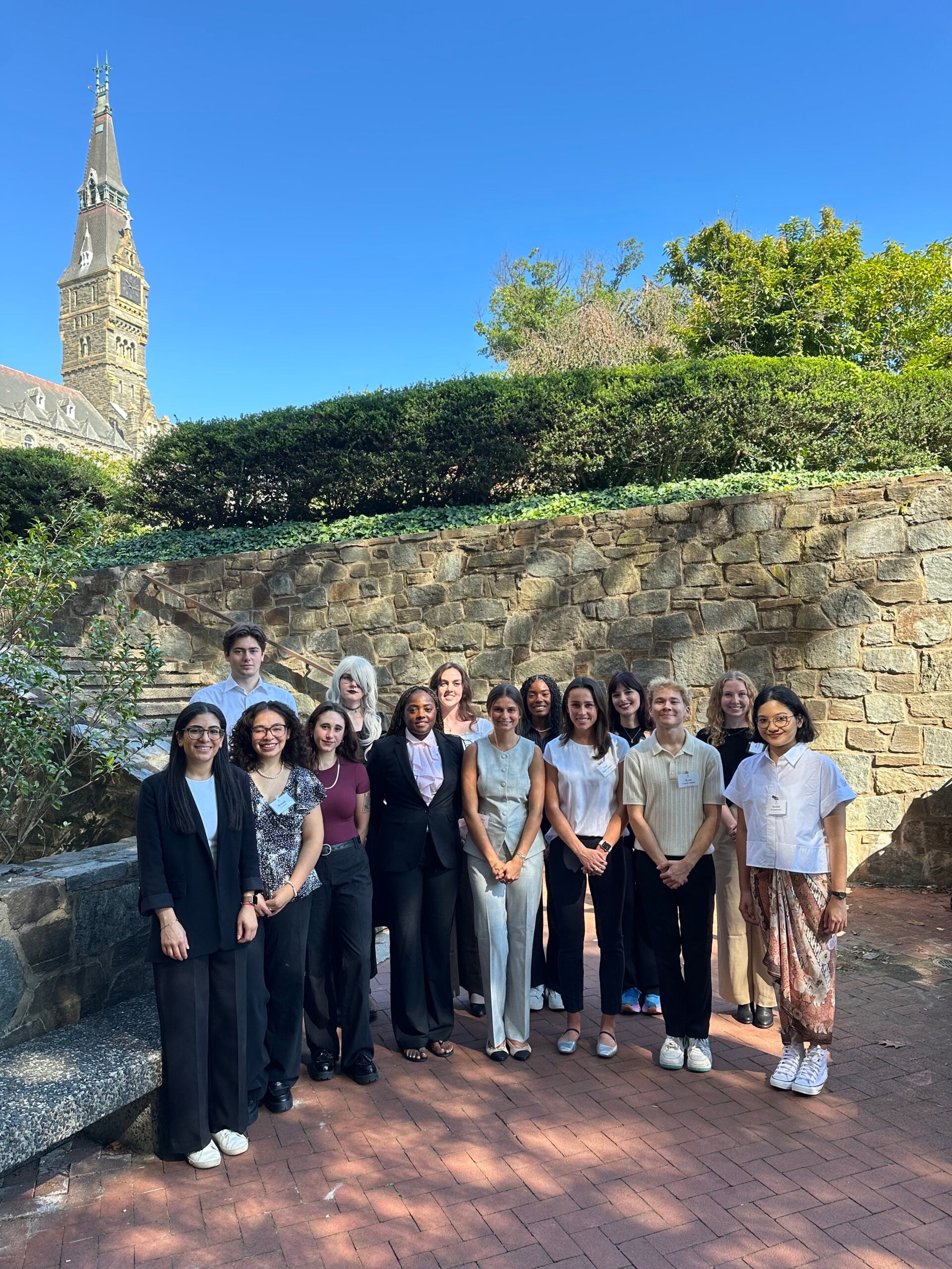 MA in Conflict Resolution Class of 2026 cohort. Fourteen students stand together with Healy Hall in the background.