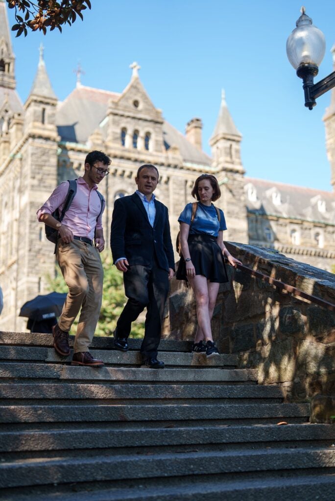 Two students and a professor walking together down steps on main campus.
