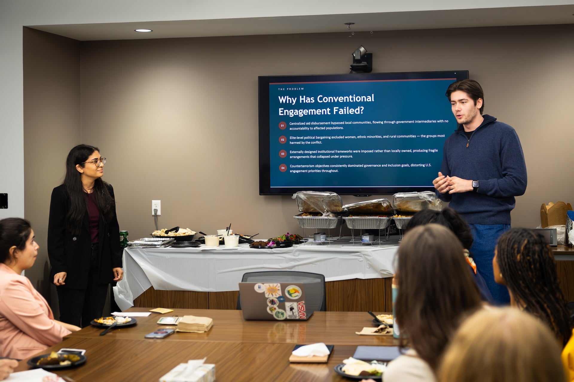 May and Antoine stand at the front of a room and give a presentation about their conflict resolution training experience.